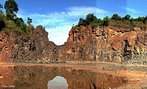 Frente de extrao dos basaltos da Formao Serra Geral, com viso da base. Esta unidade, da Era Mesozica - Perodo Cretceo, registra o intenso vulcanismo que iria iniciar a separao dos continentes Africano, Sul-americano, Antrtico, Australiano e Indiano, atravs do maior vulcanismo do tipo fissural ocorrido no globo, que originou a sequncia Serra Geral. </br></br> Palavras-chave: Dimenso Socioambiental. Econmica. Territrio. Lugar. Regio. Basalto. Rochas. Afloramento. Serra Geral. Relevo. Solo. 